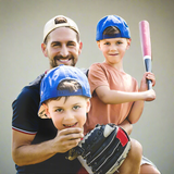 Man and two boys with baseball caps and a bat, posing together.