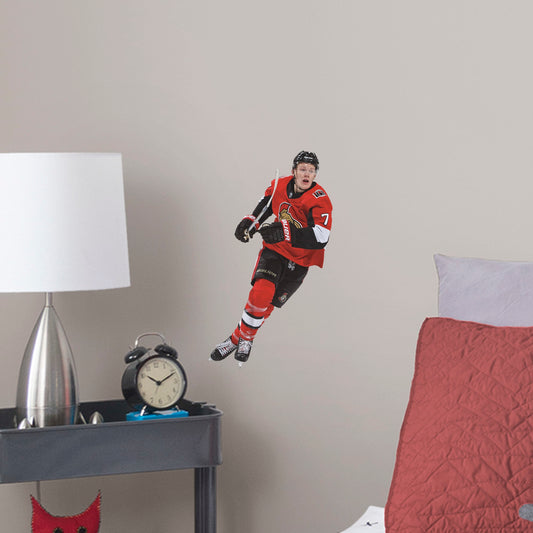 Large Athlete + 2 Team Decals (9"W x 16.5"H) Power forward Brady Tkachuk quickly made his mark in the NHL when he lead the Senators to victory, and now he's skating to life in your office, bedroom, or fan room in this Officially Licensed NHL wall decal. Ottawa fans and NHL fanatics alike will love the touch of action that Tkachuk brings, and this durable and removable wall decal will definitely stand up to the challenge, no matter how many times you restick it!