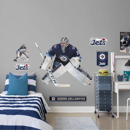 Life-Size Athlete + 11 Decals (55"W x 46"H) Opposing teams should be worried when they see Connor Hellebuyck in the goal, and now you can bring his epic defense skills to life in your own home with this Officially Licensed NHL removable wall decal. Pictured here ready to stop any puck that comes his way, this wall decal of Hellebuyck will make the perfect addition to your bedroom, office, or fan room, and it even makes a great gift for your favorite Jets fanatic!