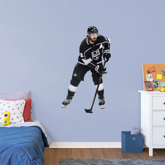 Giant Athlete + 2 Decals (29"W x 51"H) Drew Doughty has been a star from the very start and now Los Angeles Kings fanatics can bring him to life in your own home with this Officially Licensed NHL Removable Wall Decal. Shown here in action in the Kings home uniform, this wall decal is durable and high quality and is sure to bring the action to your bedroom, office, or fan room. 