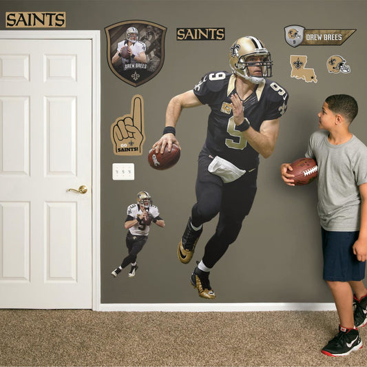 Life-Size Athlete +11 Decals (42"W x 78"H) Super Bowl MVP, NFL Sportsman of the Year, and perennial fan favorite Drew Brees hustles across your man cave wall with this durable vinyl wall decal. Showcasing the Saints' signature black and old gold with the home game uniform, this decal turns your sports bar, bedroom, or dorm room into your personal Superdome. The reusable, high quality vinyl won't damage walls, making it the perfect choice if you need to take your Saints fandom on the road.
