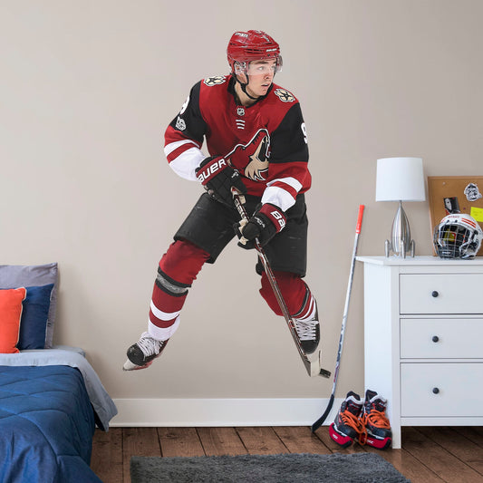 Life-Size Athlete + 1 Decal (46"W x 77"H) Drafted seventh overall in the 2016, left wing player Clayton Keller is melting ice at Gila River Arena in Glendale. Cheer on Kellsy as he leads the Coyotes on to another championship with this distinctive colorful officially licensed NHL wall decal. Make a slap shot on a wall in your home, office, or coyote fan-den with this giftable reusable NHL decal. Perfect gift idea for a fan!